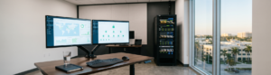 Dual monitor workstation displaying a global threat map and network security dashboard